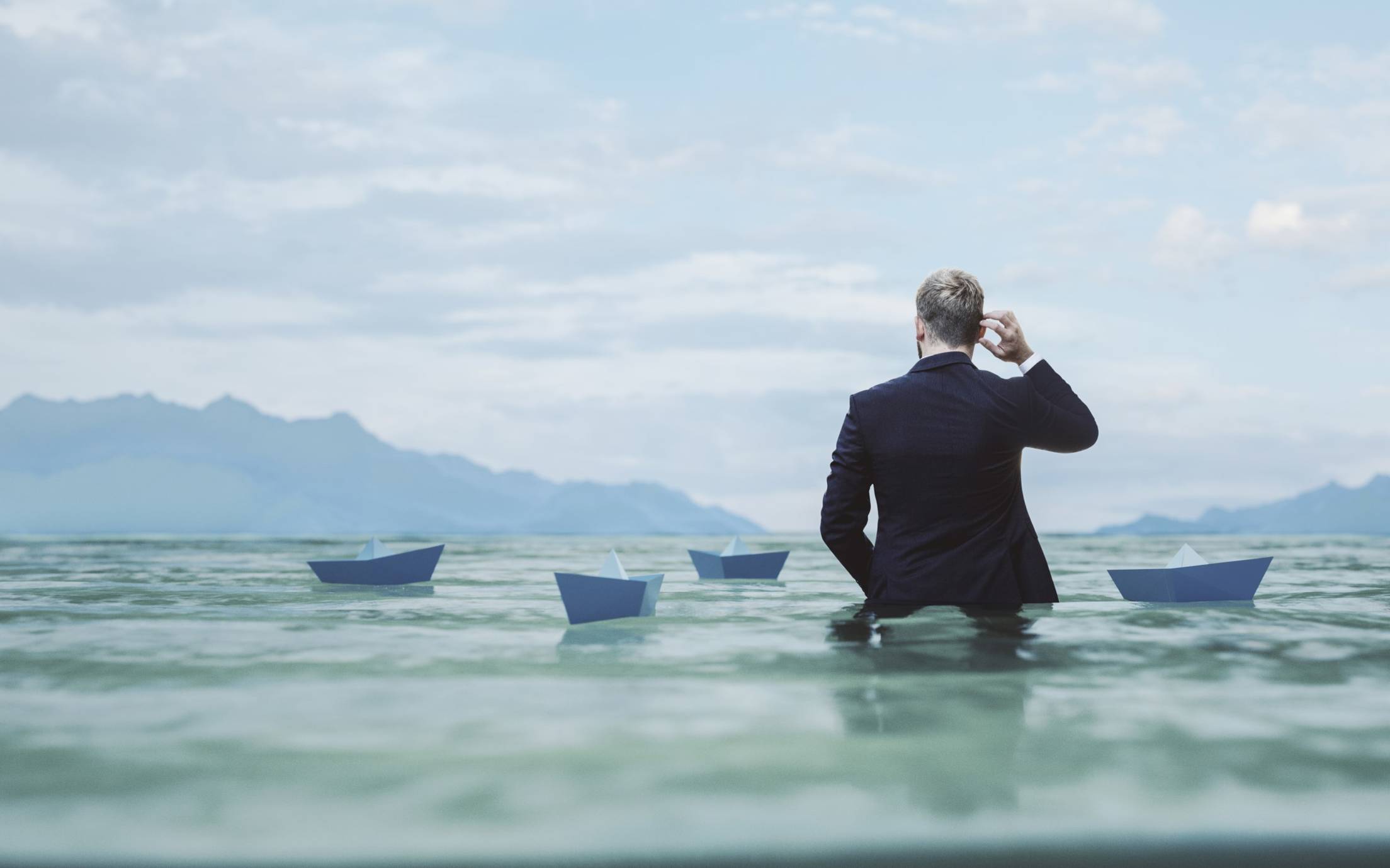 Man wading among paper ships